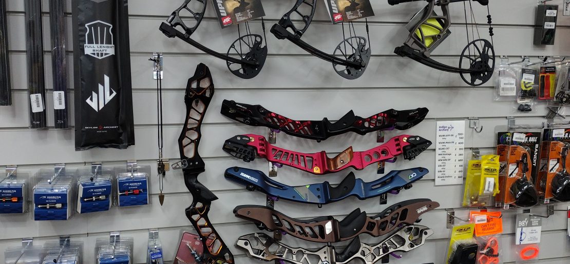 A section of wall in our shop that has 3 compound bows and various premium level recurve risers.